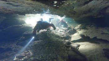 To dykker på vei inn i et vannfylt grotte. 