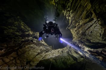 En dykker i vannfylt grotte. Foto. 